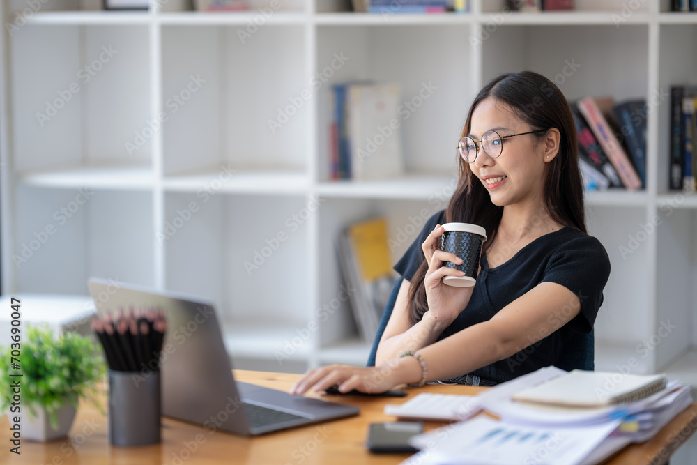 Freelance Asian businessperson, businesswoman sitting and enjoying hot coffee, pay attention on the laptop screen while relaxing. Freelance Asian businessperson, businesswoman sitting and enjoying hot coffee, pay attention on the laptop screen while relaxing.