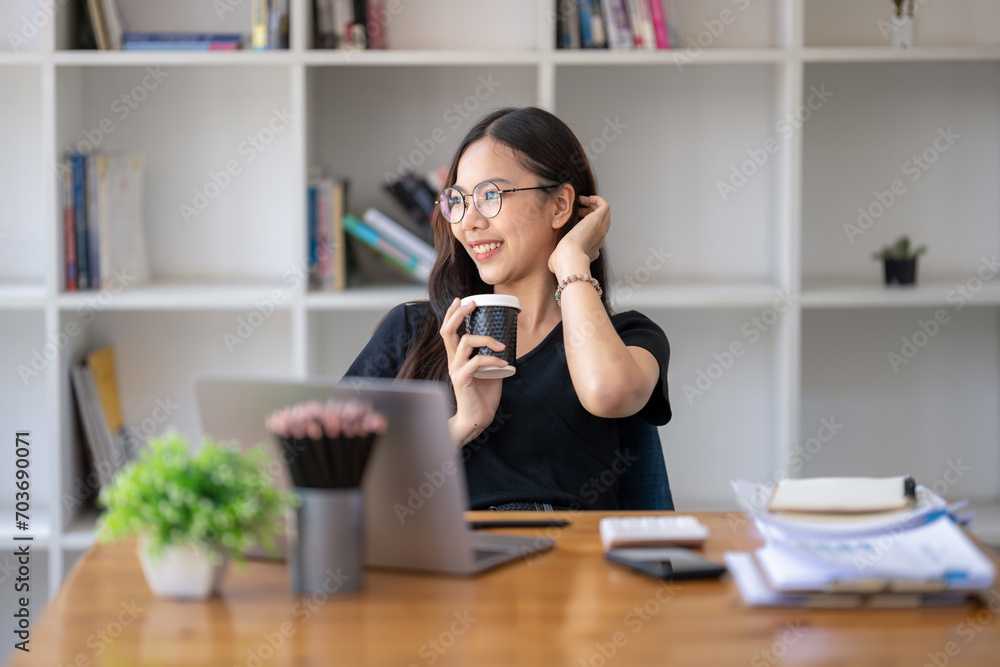 Freelance Asian businessperson, businesswoman sitting and enjoying hot coffee Look out the window, smile and imagine being in a good mood. Freelance Asian businessperson, businesswoman sitting and enjoying hot coffee Look out the window, smile and imagine being in a good mood.