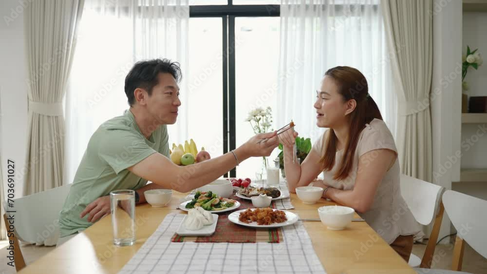 Asian couple feeding with chopsticks on table in their home, family relationship concept
Asian couple feeding with chopsticks on table in their home, family relationship concept