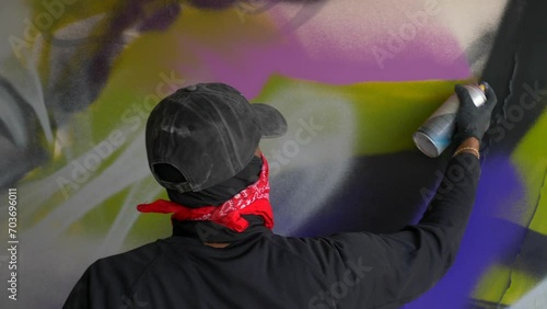 Graffiti artist spraying a colorful portrait mural on a wall