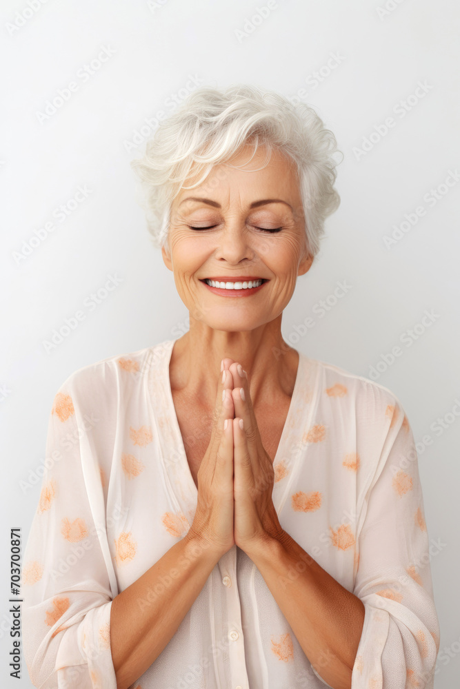Smiling elderly woman with closing eyes makes yoga