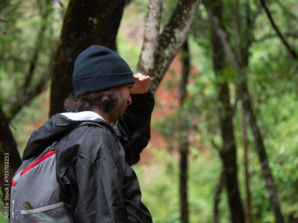 Jeune campeur de profil, cherchant son chemin dans la forêt