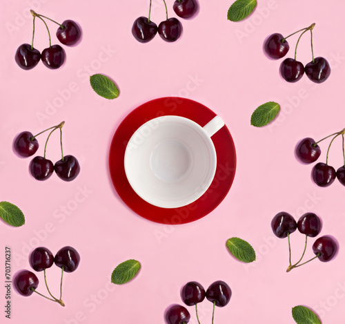 Empty white cup for tea, red cherries and mint on the pink background. Copy space. Top view. photo