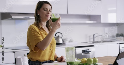 Woman, blender and drinking juice in kitchen for diet, detox and healthy food with green breakfast drink or smoothie. Nutritionist or person with protein shake, fruits and vegetable for wellness photo