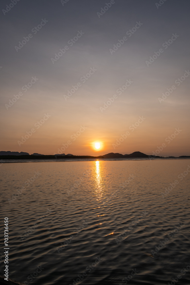 Naklejka premium Sunrise view with colorful sky and the sea, with silhouette of the forest on the background