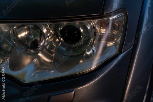 Close up on car headlights. The glass coating on the headlight surface is cloudy. Night light in the evening. © thongchainak