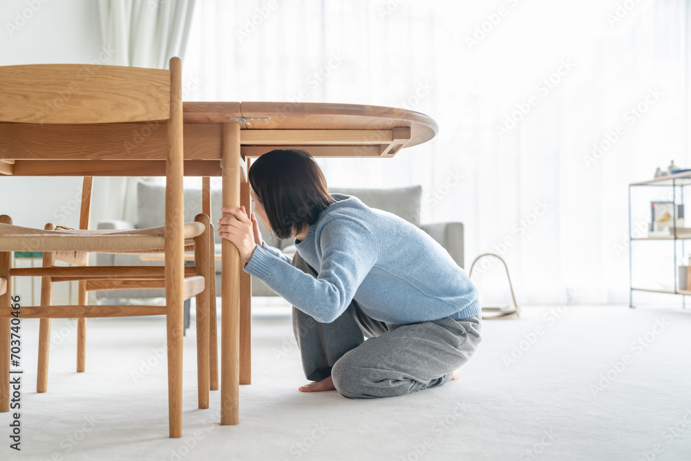 地震で机の下に潜る女性 地震で机の下に潜る女性