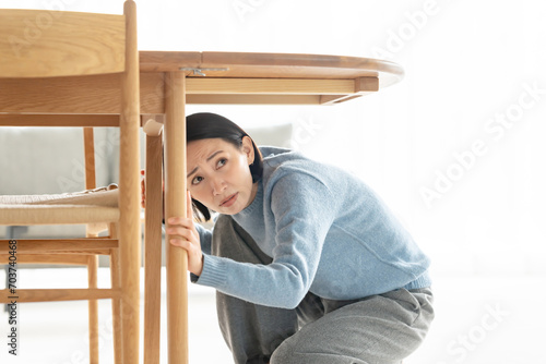 地震で机の下に潜る女性