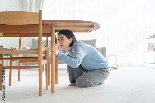 地震で机の下に潜る女性