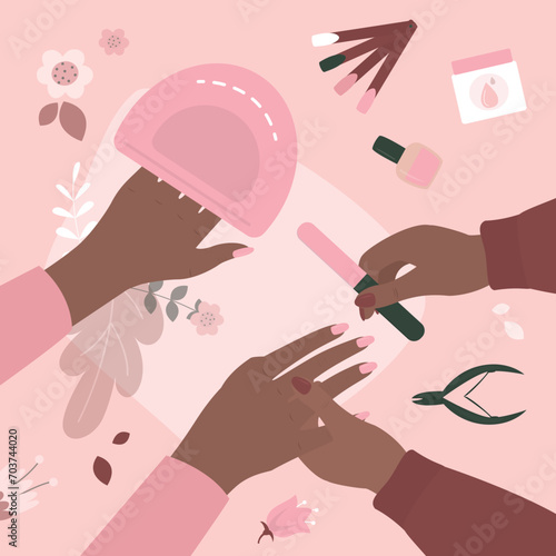 Manicurist uses nailfile and nail polish for manicure procedure. African american woman at manicure salon. Beauty salon, manicure tools on table. Nails and beauty.