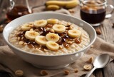 Bowl of oatmeal porridge with banana and caramel sauce on rustic table hot and healthy breakfast
