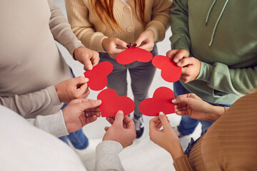 Group of friends exchanging valentines. Cropped shot of young adult people standing in circle and giving each other red heart shaped valentine cards. Love, care, affection, connection concept