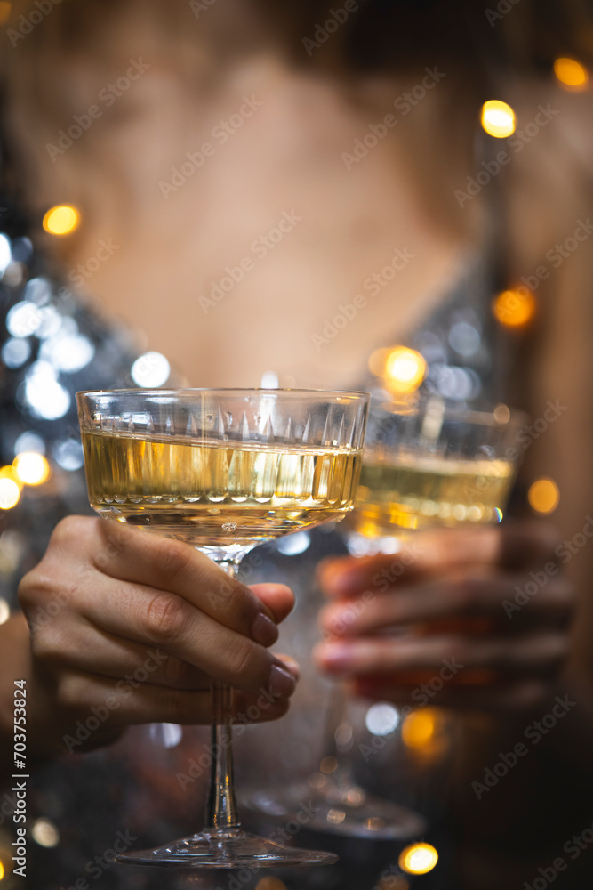 The girls pour champagne into round glasses. Women in a sparkling dress. Full cocktail creamers - le coupe