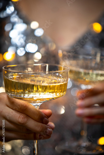 The girls pour champagne into round glasses. Women in a sparkling dress. Christmas garland