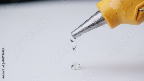 Close-up of hot glue coming out of a glue gun. Hot glue is squeezed out of the gun.