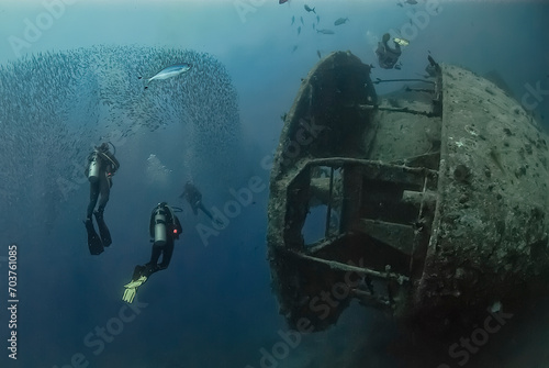 Divers swim alongside the legendary SS Thistlegorm, a World War II shipwreck in the Red Sea, teeming with marine life and historical intrigue