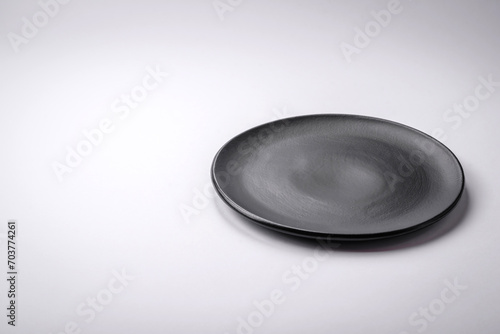 Empty round ceramic plate on a plain background, flatley with copy space