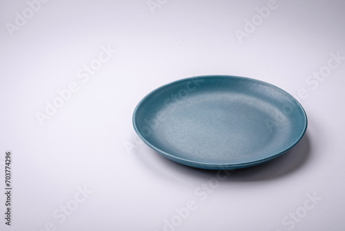 Empty round ceramic plate on a plain background, flatley with copy space