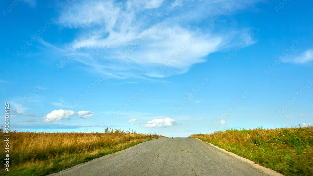 Travelling by car. Asphalt road among summer fields,blue sky