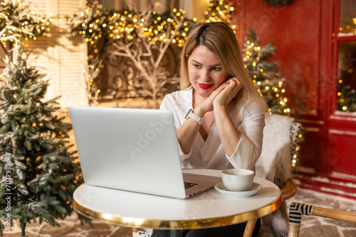 Smiling adult on video call online conference in christmas. Festive young woman talking to friends and family on laptop for seasonal winter celebration