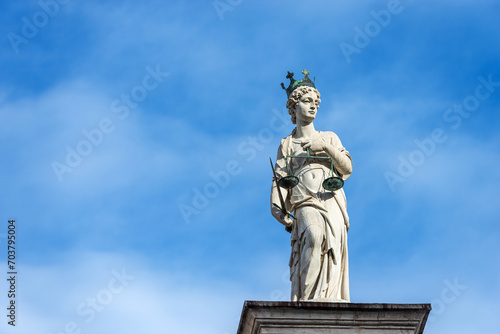 Marble Statue of Justice. Goddess of justice holding law scales and a sword (Themis). Freedom square (Piazza della Liberta), Udine, Friuli-Venezia Giulia, Italy, Europe.