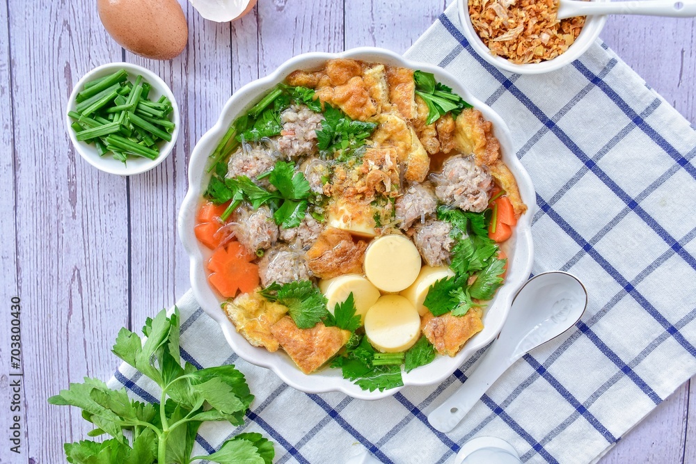 Thai omelet soup with bean curd and minced pork with vermicelli and vegetables ,top view food table, white bowl, home cooked 