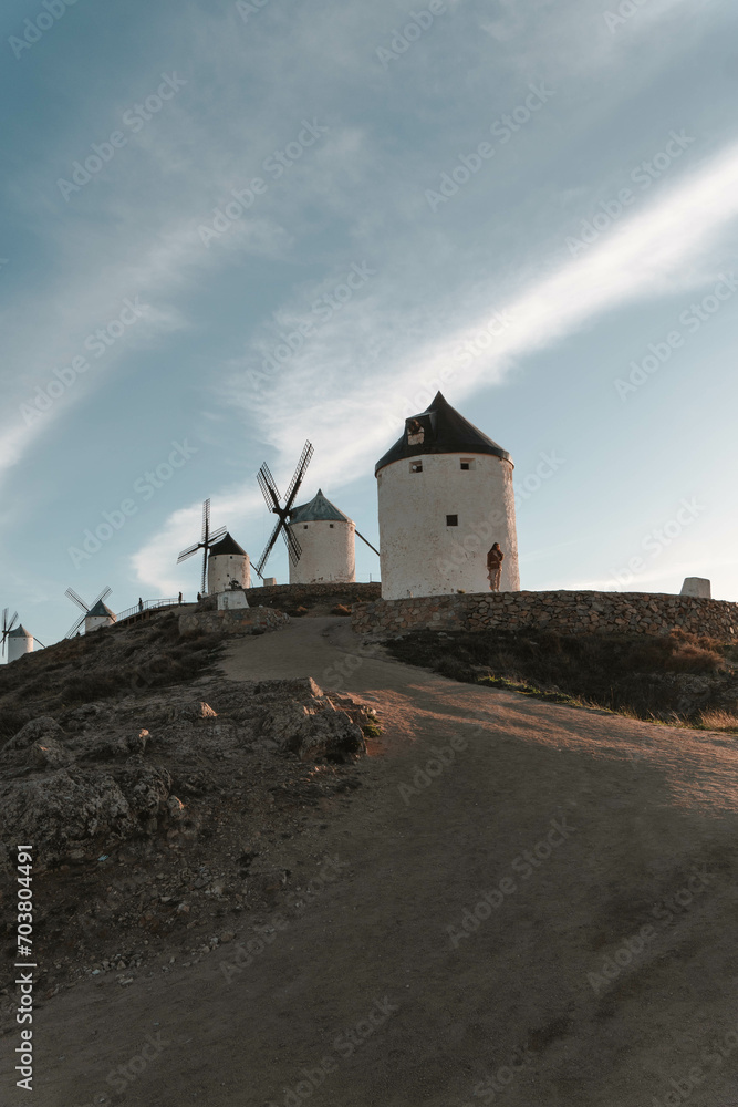 Una chica observando molinos de viento al atardecer