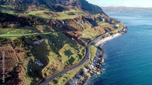 Northern Ireland, UK, Atlantic coast with cliffs. Causeway Coastal Route with car and parking.. One of the most scenic coastal roads in Europe. Aerial 4K video. Winter, sunrise light