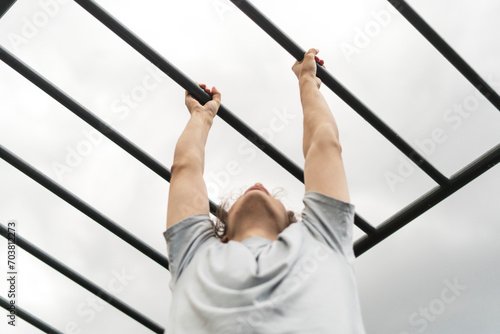 Foto fitness workout on monkey bars outdoors, arm muscles training, climbing on ladde