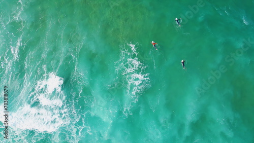 Drone shot surfers swimming in ocean water waiting waves. Extreme active hobby