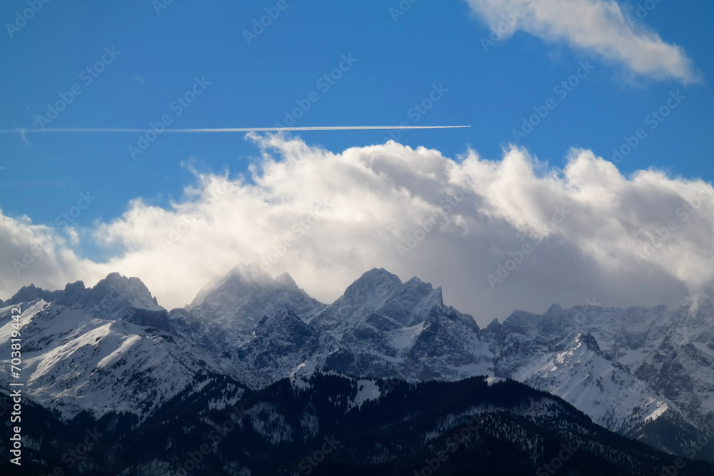 Obraz na płótnie Widok na ośnieżone góry i przelatujący samolot nad nimi. Szczyty Tatr Wysokich. w salonie