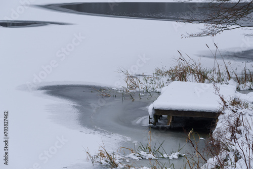 WINTER ATTACK - A frozen lake and a wooden fishing and recreation platform covered with snow photo