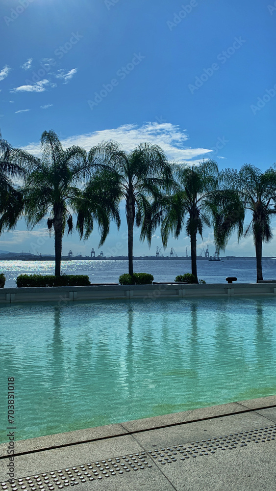 Fototapeta premium Tranquil Poolside Retreat: Clear Blue Skies and Reflective Waters.