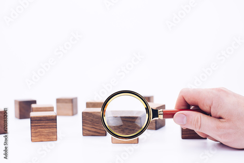 Scattered wooden cubes on a white background. Blocks. Magnifying glass. Research and meticulousness. Detective