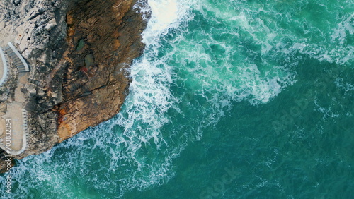 Aerial amazing rocky coast washed sea water with foam. Waves crashing on cliff.