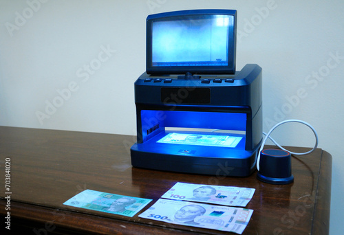 money detector placed on a counter, banknote placed in the receiver