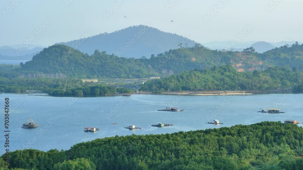 Floating fish cages and fish traps in the afternoon against the backdrop of a calm ocean and a hilly green tropical island with boats and seabirds passing by.. Floating fish cages and fish traps in the afternoon against the backdrop of a calm ocean and a hilly green tropical island with boats and seabirds passing by..
