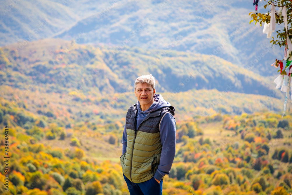 Adult man standing on the background of autumn mountains