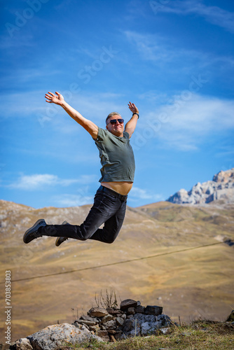 A joyful man on the top of a mountain experiences the flight of the soul and freedom, enveloped in the stunning beauty of the mountainous landscape