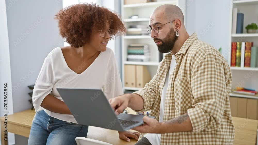 Confident man and woman partners enjoying their work at the office, smiling as they use laptop Confident man and woman partners enjoying their work at the office, smiling as they use laptop