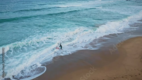 Unknown surfer entering sea aerial shot. Surfboarder putting board on water
