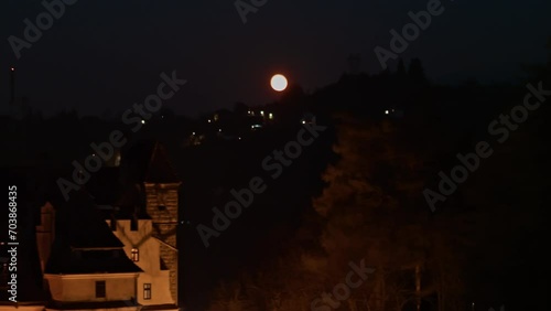 Establishing aerial shot of medieval Bran Dracula Castle in Transylvania. Spooky Halloween castle shrouded in mist and illuminated by the light of the full moon at night photo