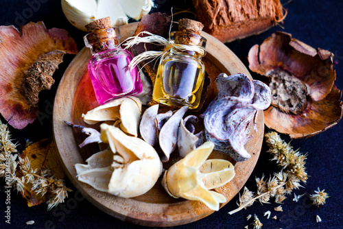 oil spa care beauty dry herb oils ingredient herbs  flower bottle rose water pink wooden bowl black background 