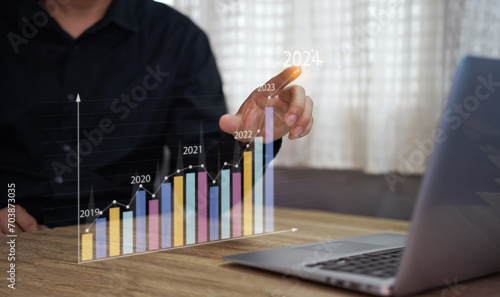 A man holding holographic graphs and stock market statistics gain profits. Concept of growth planning and business strategy. Corporate strategy for finance, operations, sales, marketing. 