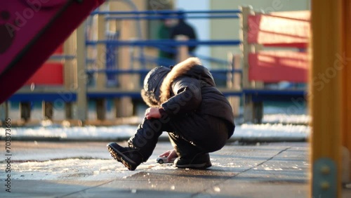 Child toddler caucasian ukrainian boy in warm winter clothes playing on a cold playground.