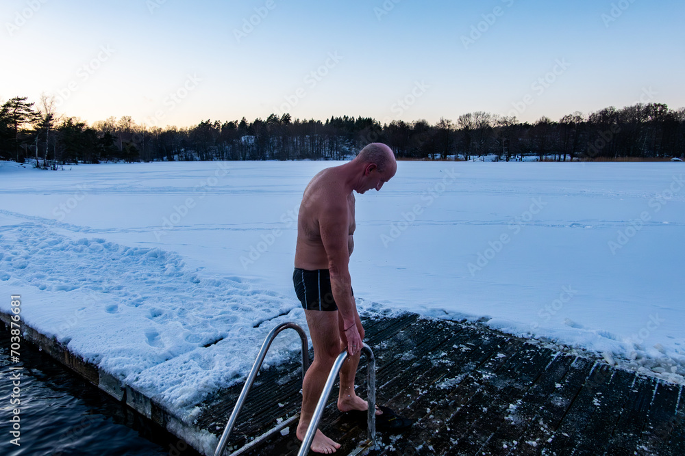 Stockholm, Sweden A man  ice bathing from a dock into a frozen lake.