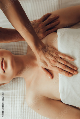 Hands of female chiropractor massaging shoulders of young woman lying on massage table. Concept of physical therapy treatment ,neck pressure point