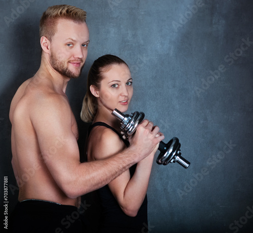 Athletic couple with a dumbells near the wall