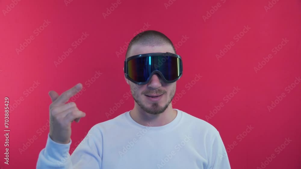 Blogger Reviews Snowboard Goggles. Expressive Blogger Broadcasts on Red Background. Man Vlogger Look at Camera Talk Make Live Video Conference, Close Up Webcam View, Videochat concept Blogger Reviews Snowboard Goggles. Expressive Blogger Broadcasts on Red Background. Man Vlogger Look at Camera Talk Make Live Video Conference, Close Up Webcam View, Videochat concept