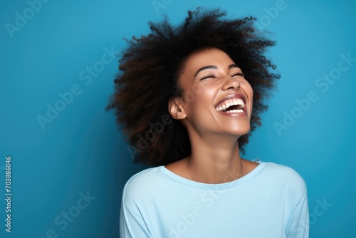 Black History Month, Portrait of happy young black woman laughing on blue background